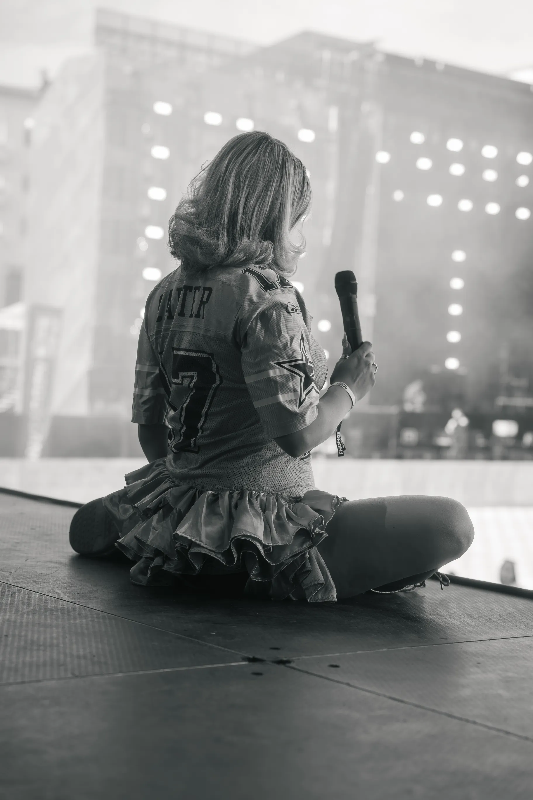 An artist sits on stage, holding a microphone