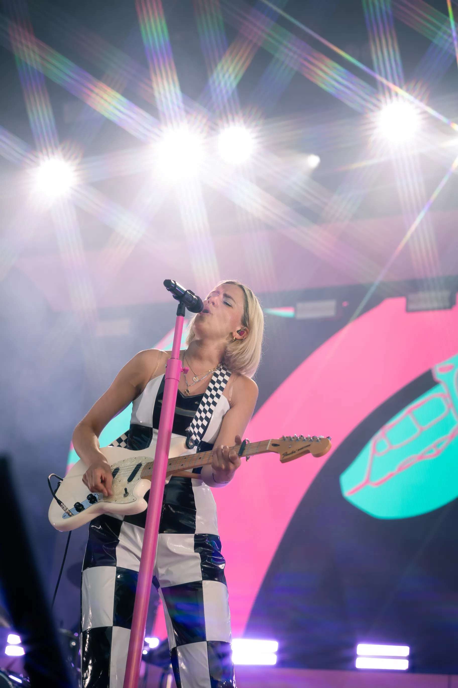 A female artist singing into a microphone while playing the guitar