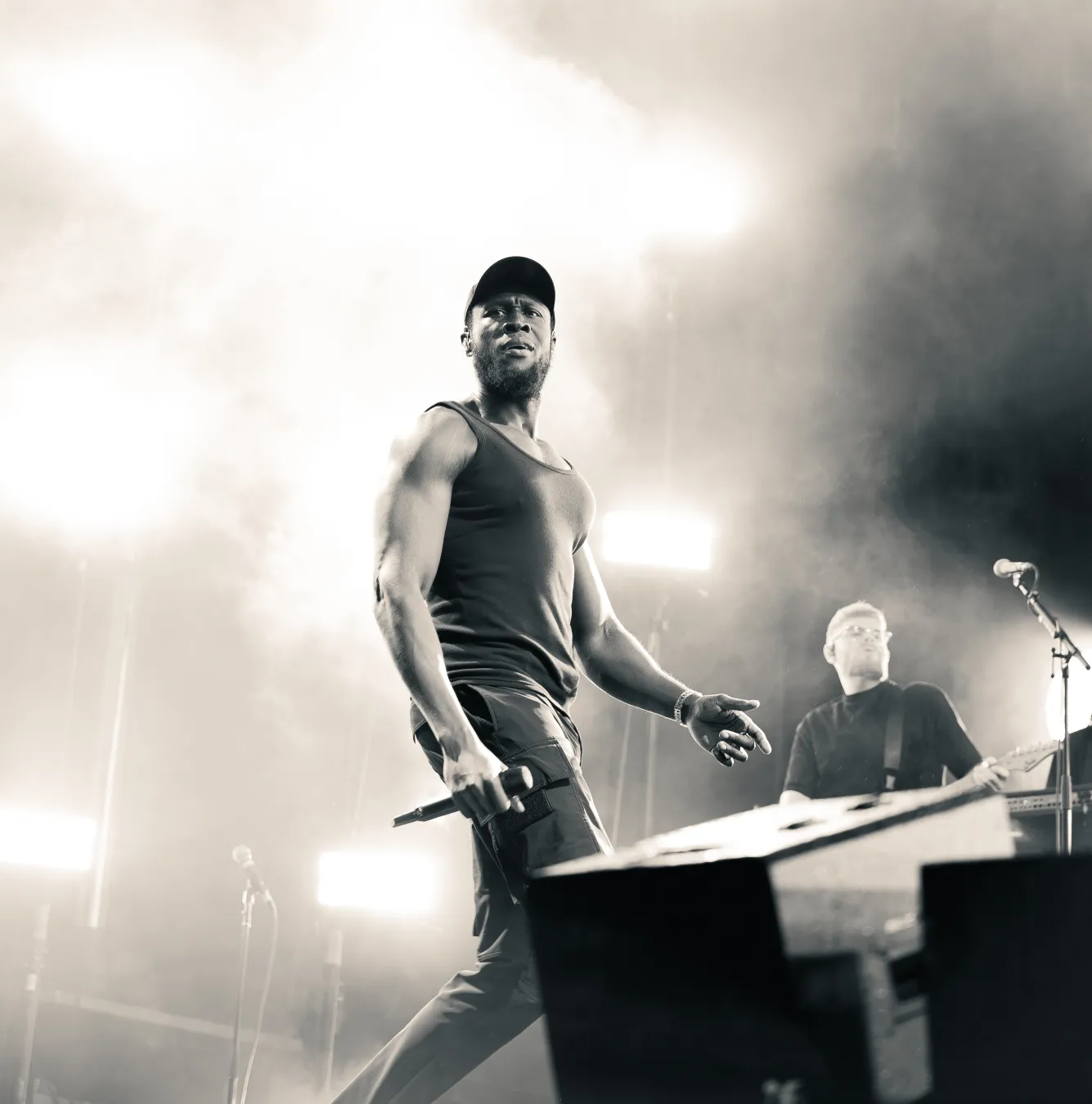 An artist singing into a microphone with one foot resting on a speaker