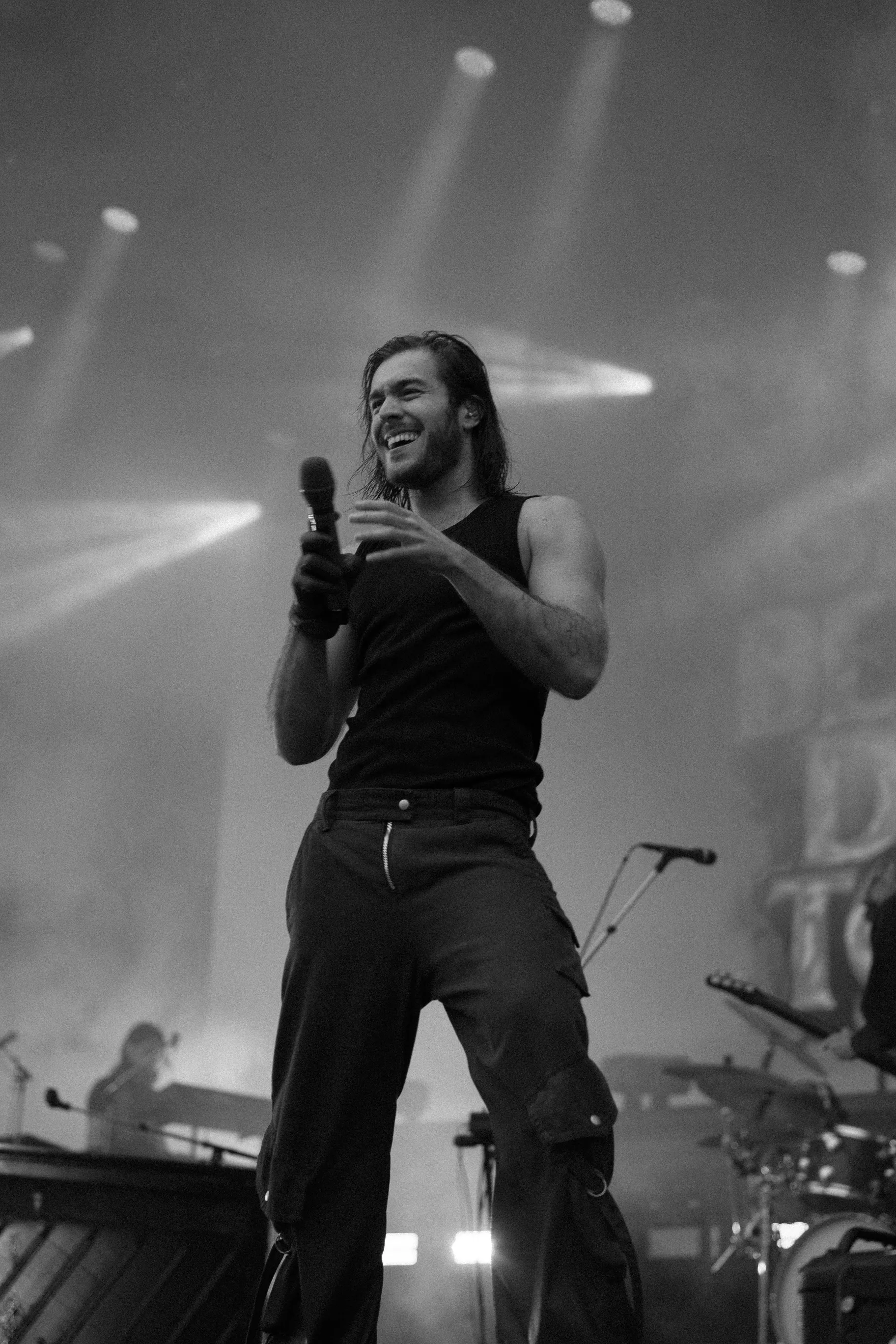 An artist smiling on stage while holding a microphone